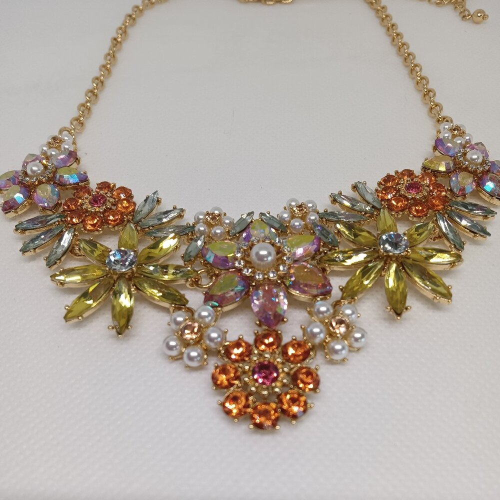 A crystal embellished floral necklace in  shades of orange, coral and yellow.